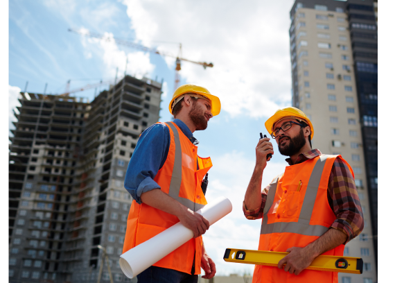 Site engineers reviewing plans in front of a construction tower